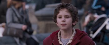 Movie still from “August Rush” (2007), directed by Kirsten Sheridan – A young boy in a red jacket looks at the camera; Close Up shot, Over the shoulder angle