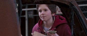 Movie still from “August Rush” (2007), directed by Kirsten Sheridan – A young boy is holding money in his hands; Close Up shot, Over the shoulder angle
