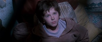 Movie still from “August Rush” (2007), directed by Kirsten Sheridan – A young boy sitting in a chair looking at the camera; Close Up shot, High angle