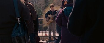 Movie still from “August Rush” (2007), directed by Kirsten Sheridan – A man playing a guitar on a bridge; Wide shot, Over the shoulder angle