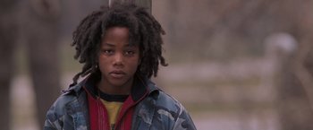 Movie still from “August Rush” (2007), directed by Kirsten Sheridan – A young man with dreads stands in front of a wooden pole; Close Up shot, Over the shoulder angle