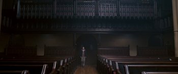 Movie still from “August Rush” (2007), directed by Kirsten Sheridan – A man standing in a room with a lot of wooden pews; Extreme Wide shot, High angle