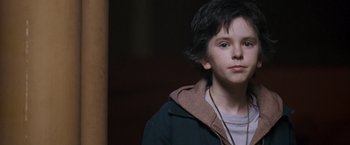 Movie still from “August Rush” (2007), directed by Kirsten Sheridan – A young boy is looking into the camera; Close Up shot, Over the shoulder angle