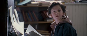 Movie still from “August Rush” (2007), directed by Kirsten Sheridan – A young boy sitting in front of a book shelf; Close Up shot, Over the shoulder angle
