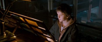 Movie still from “August Rush” (2007), directed by Kirsten Sheridan – A young boy sitting in front of an open book; Medium shot, High angle