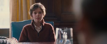 A young boy sitting at a table in front of a window