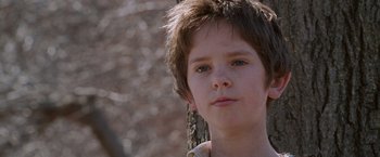 Movie still from “August Rush” (2007), directed by Kirsten Sheridan – A young boy is standing next to a tree; Close Up shot, Low angle
