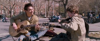 Movie still from “August Rush” (2007), directed by Kirsten Sheridan – Two young men sitting on the ground with guitars; Medium shot, Low angle