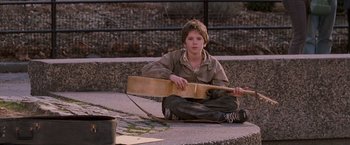 Movie still from “August Rush” (2007), directed by Kirsten Sheridan – A boy sitting on the ground holding a guitar; Wide shot, High angle
