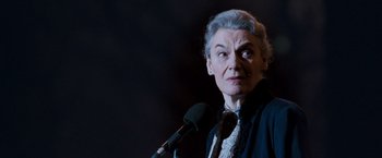 Movie still from “August Rush” (2007), directed by Kirsten Sheridan – An older woman is speaking into a microphone; Close Up shot, Low angle