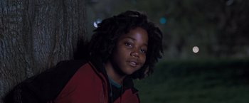 Movie still from “August Rush” (2007), directed by Kirsten Sheridan – A young boy with a dreadlocks standing next to a tree at night; Close Up shot, Low angle