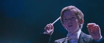 Movie still from “August Rush” (2007), directed by Kirsten Sheridan – A person in a suit holding a white stick; Close Up shot, Low angle