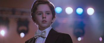 Movie still from “August Rush” (2007), directed by Kirsten Sheridan – A young boy in a suit and bow tie; Close Up shot, Low angle