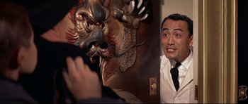 Movie still from “Auntie Mame” (1958), directed by Morton DaCosta – A man standing next to a wall with a dragon; Close Up shot, Over the shoulder angle