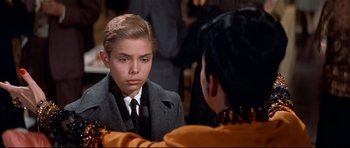 Movie still from “Auntie Mame” (1958), directed by Morton DaCosta – A young man in a suit looking at his reflection in a mirror; Close Up shot, High angle