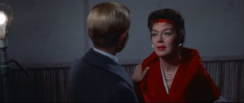 A woman in a red jacket looking at a boy in a blue suit