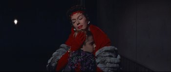 Movie still from “Auntie Mame” (1958), directed by Morton DaCosta – An older woman in a red dress and a young girl; Medium shot, Low angle
