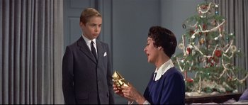 Movie still from “Auntie Mame” (1958), directed by Morton DaCosta – An older woman is giving a young boy a present; Medium shot, Over the shoulder angle