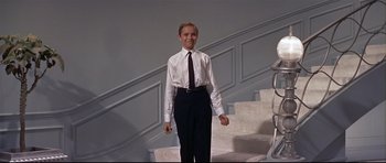 Movie still from “Auntie Mame” (1958), directed by Morton DaCosta – A young man in a white dress shirt and black tie; Medium shot, Low angle