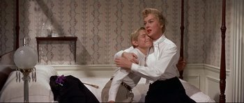 Movie still from “Auntie Mame” (1958), directed by Morton DaCosta – A man and a woman hugging each other in front of a mirror; Medium shot, Over the shoulder angle