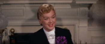 Movie still from “Auntie Mame” (1958), directed by Morton DaCosta – A person wearing a suit and tie; Close Up shot, Over the shoulder angle