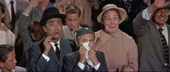 Movie still from “Auntie Mame” (1958), directed by Morton DaCosta – An older man and a young boy and a young woman and an older man and a young woman; Medium shot, Low angle