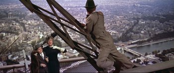 Movie still from “Auntie Mame” (1958), directed by Morton DaCosta – A man in a hat is climbing up a fence; Wide shot, High angle