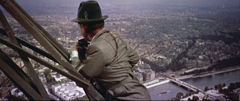 Movie still from “Auntie Mame” (1958), directed by Morton DaCosta – A man in a hat and a jacket taking a picture of a city; Wide shot, High angle