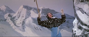 Movie still from “Auntie Mame” (1958), directed by Morton DaCosta – A woman holding a ski pole while standing in the snow; Medium shot, Low angle