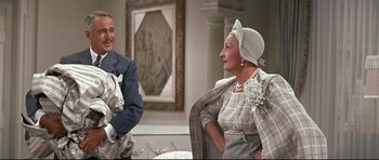 Movie still from “Auntie Mame” (1958), directed by Morton DaCosta – A man and a woman sitting next to each other in a room; Medium shot, Over the shoulder angle