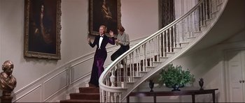 Movie still from “Auntie Mame” (1958), directed by Morton DaCosta – Two women are walking down the stairs of a house; Wide shot, Low angle