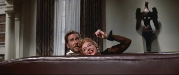 Movie still from “Auntie Mame” (1958), directed by Morton DaCosta – A man and a woman sitting on top of a couch; Medium shot, Low angle