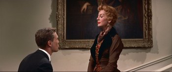 Movie still from “Auntie Mame” (1958), directed by Morton DaCosta – An older woman in a brown dress and a young man in a suit; Medium shot, Low angle