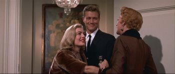 Movie still from “Auntie Mame” (1958), directed by Morton DaCosta – A man and a woman standing next to each other in a room; Medium shot, Over the shoulder angle