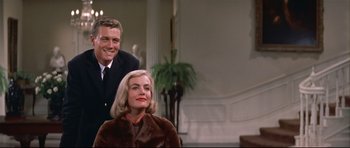 Movie still from “Auntie Mame” (1958), directed by Morton DaCosta – A man standing next to a woman wearing a fur coat; Medium shot, Low angle