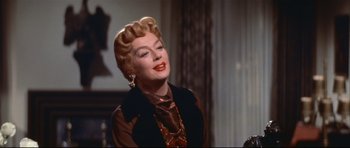 Movie still from “Auntie Mame” (1958), directed by Morton DaCosta – An old photo of a woman in a brown outfit; Close Up shot, Low angle