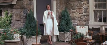 Movie still from “Auntie Mame” (1958), directed by Morton DaCosta – A woman in a white dress standing in front of a house; Medium shot, Low angle
