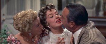 Movie still from “Auntie Mame” (1958), directed by Morton DaCosta – A group of people that are standing around each other; Close Up shot, Over the shoulder angle