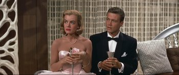 Movie still from “Auntie Mame” (1958), directed by Morton DaCosta – A man and a woman in formal wear holding champagne glasses; Medium shot, High angle