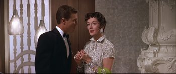 Movie still from “Auntie Mame” (1958), directed by Morton DaCosta – A man and a woman standing next to each other; Medium shot, Over the shoulder angle