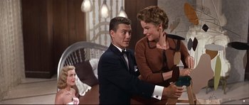 Movie still from “Auntie Mame” (1958), directed by Morton DaCosta – A man and a woman are shaking hands in a room; Medium shot, Low angle