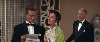Movie still from “Auntie Mame” (1958), directed by Morton DaCosta – A man and a woman standing next to each other; Medium shot, Over the shoulder angle