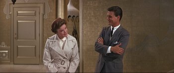 Movie still from “Auntie Mame” (1958), directed by Morton DaCosta – A man and a woman standing next to each other; Medium shot, Over the shoulder angle