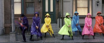 Movie still from “Austin Powers in Goldmember” (2002), directed by Jay Roach – A group of people in raincoats and holding umbrellas; Wide shot, Overhead angle