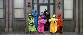 Movie still from “Austin Powers in Goldmember” (2002), directed by Jay Roach – A group of people dressed in raincoats and holding umbrellas; Wide shot, Low angle