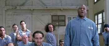 Movie still from “Austin Powers in Goldmember” (2002), directed by Jay Roach – A group of men standing next to each other in front of a building; Medium shot, Low angle
