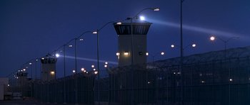 Movie still from “Austin Powers in Goldmember” (2002), directed by Jay Roach – A tall tower with lights on top of it near a fence; Extreme Wide shot, Low angle