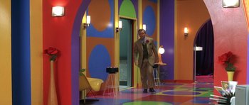Movie still from “Austin Powers in Goldmember” (2002), directed by Jay Roach – A man in a suit and tie standing in front of a doorway; Wide shot, High angle