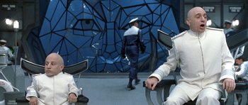 Movie still from “Austin Powers in Goldmember” (2002), directed by Jay Roach – A man in a white hat is standing in front of a wall; Medium shot, High angle