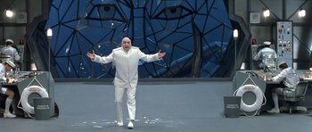 Movie still from “Austin Powers in Goldmember” (2002), directed by Jay Roach – A man in a white suit standing in front of a building; Wide shot, Low angle